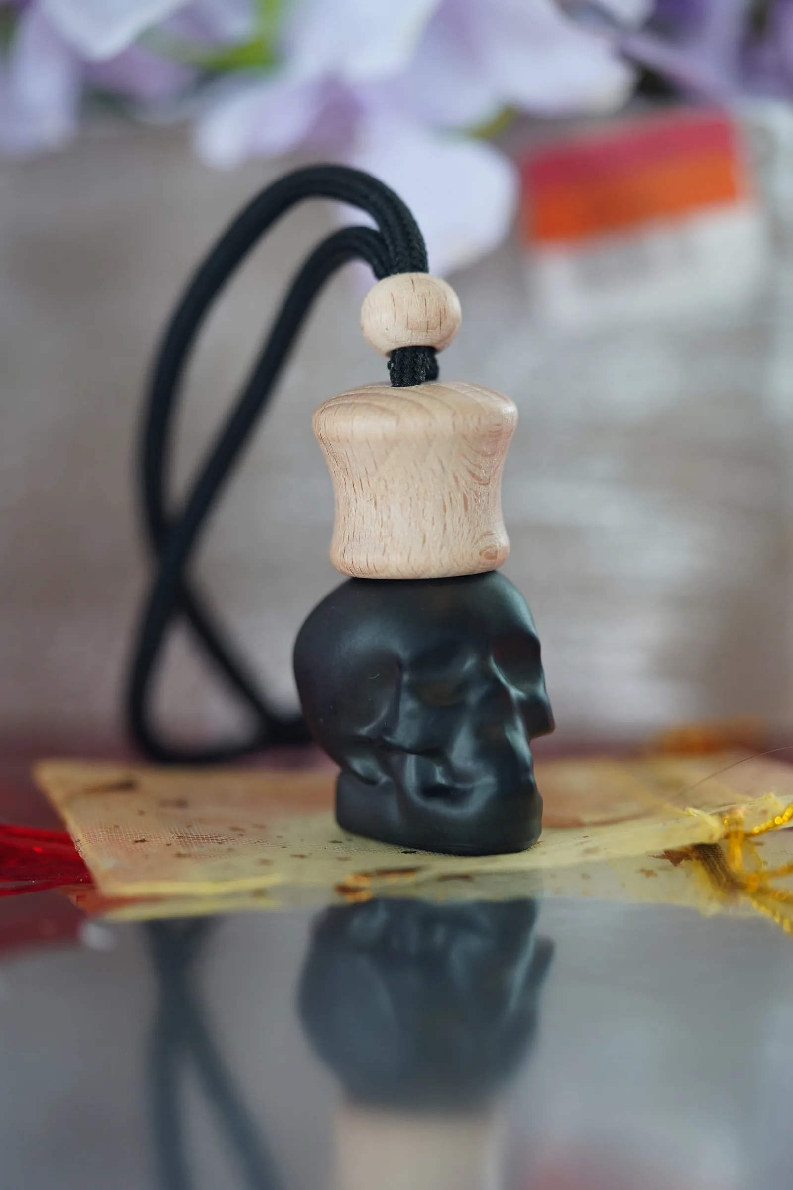 Black skull-shaped hanging car freshener with a natural wood cap